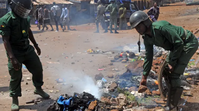 Police officers clear a burning barricade on a street in Conakry in March 2018