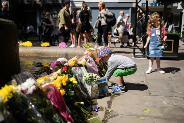 Young boy lays flowers at memorial