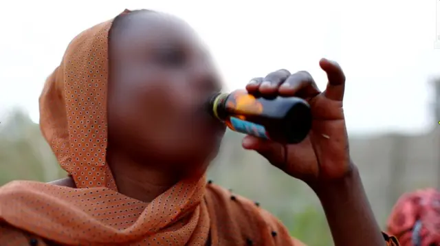 A woman drinks codeine cough syrup