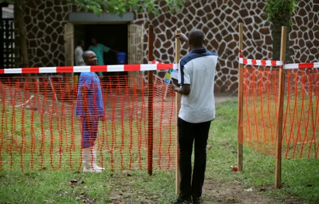 A resident speaks to a medical worker through a cordon ribbon, near the isolation facility prepared to receive suspected Ebola cases, at the Mbandaka General Hospital, in Mbandaka