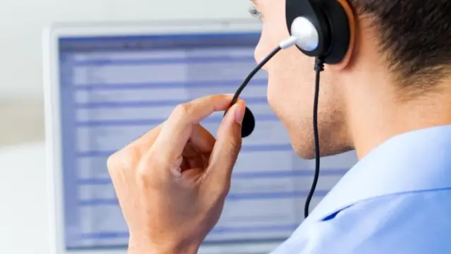 Man wearing headset looking at computer monitor