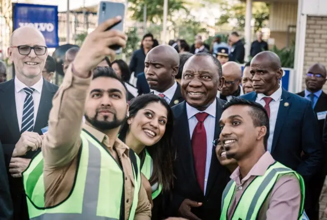 South Africa"s President Cyril Ramaphosa (C) poses for a "selfie" with young entrepreneurs during a visit to the Volvo Automobile factory plant in Durban on May 19, 2018