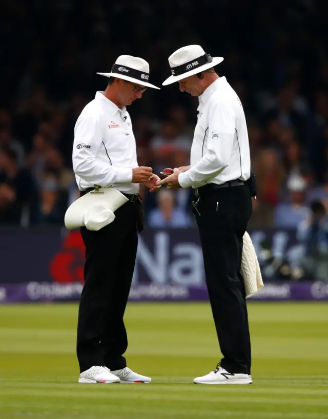 Umpires check the condition of the ball