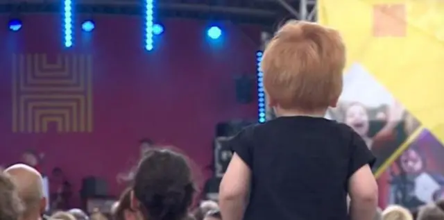 Child on and adults shoulders watching a band