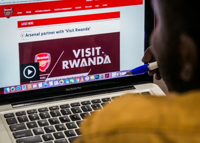 An Arsenal fan looks at the website of England"s Arsenal football Club that shows Rwanda"s new tourism promotion logo in Kigali on May 23, 2018.