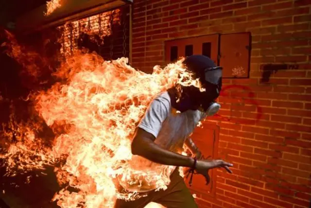 A rioter on fire running from police in Venezuela