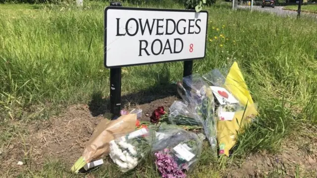 Road sign with floral tributes on the ground