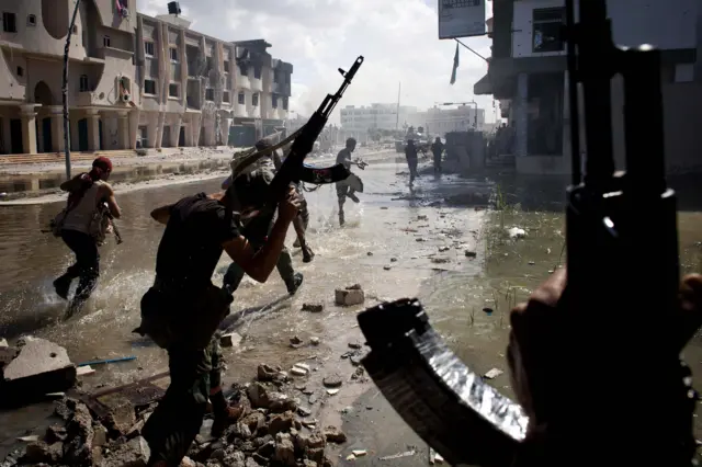 National Transitional Council (NTC) fighters take part in a street battle in the center of the city on October 14, 2011 in Sirte, Libya.