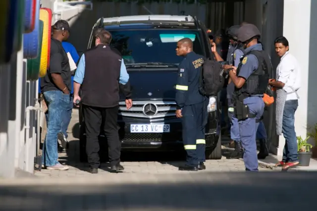 Police stand next to a car during the raids