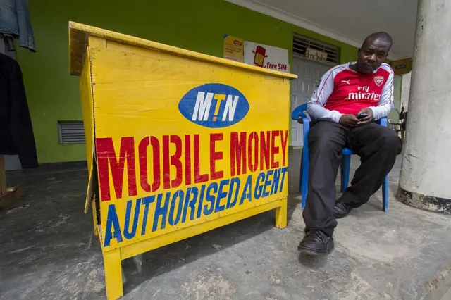 An MTN mobile money agent sits next to his business in Kisoro district, about 480 km west of the capital Kampala, on November 18, 2015. MTN Uganda has appealed a court award of Shs 2.3 billion (around 662,000 dollars or 620,700 euro) to electronic money provider EzeeMoney for sabotaging its business.