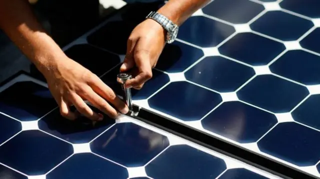 Hands working on solar panel