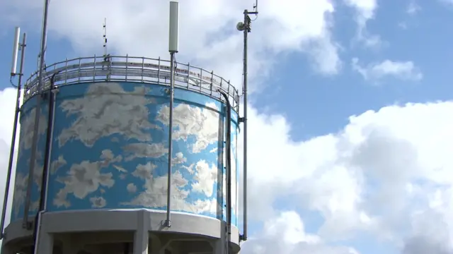 Newton Ferrers water tower painted with a blue and white skyscape