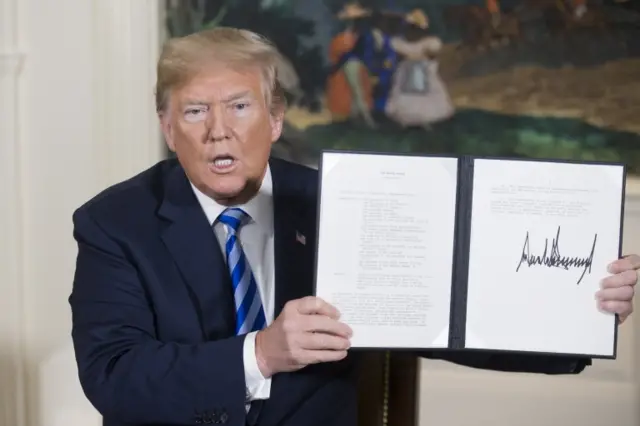 Trump holds up a signed presidential memorandum on Iran