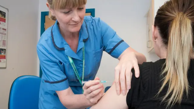 Midwife gives vaccine to woman