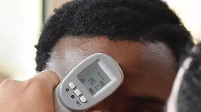 A passenger having their temperature checked at an airport