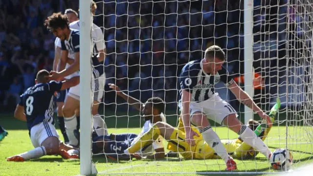 West Bromwich Albion's Northern Irish midfielder Chris Brunt grabs the ball as teammates mob West Bromwich Albion's English midfielder Jake Livermore