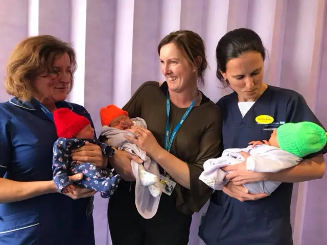 Maternity staff with babies in coloured hats