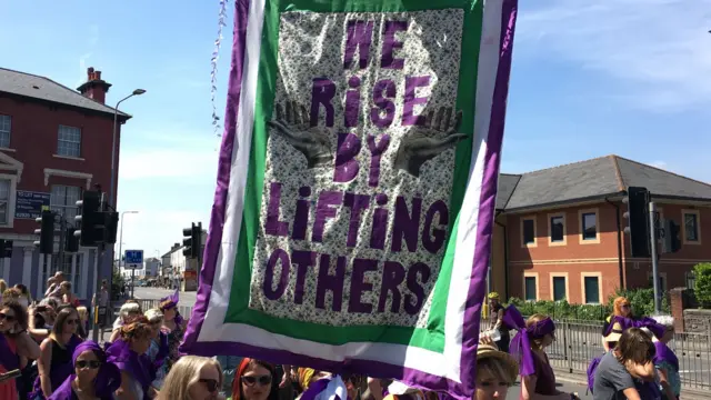 Banner saying 'We rise by lifting others' at the Cardiff Procession