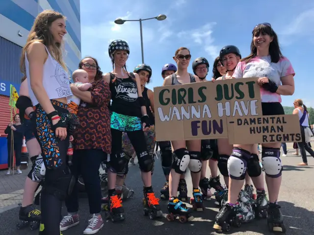 Group of female rollerbladers standing with their sign