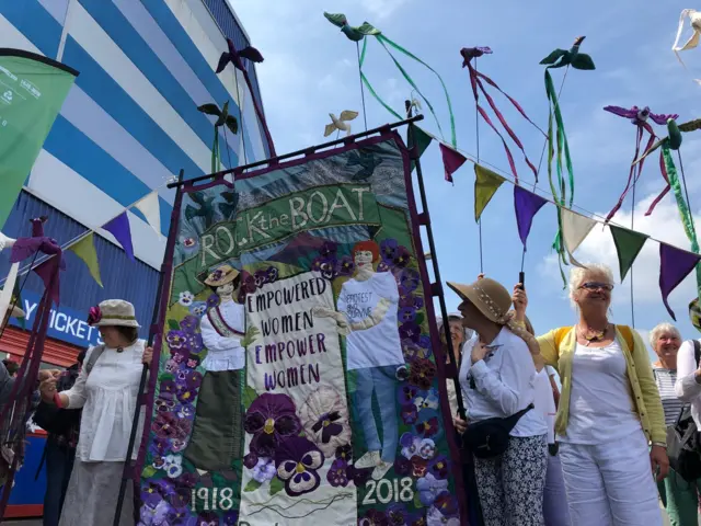 3 Processions participants with banner saying Empowered women empower women