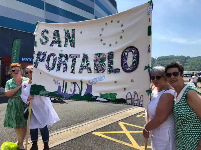 Sian, Corrie, Ashley and Laura standing with their banner that reads San Portablo