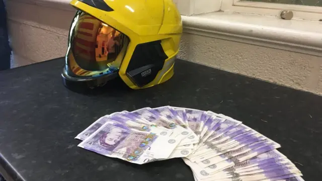 The £1,000 next to a firefighter's helmet