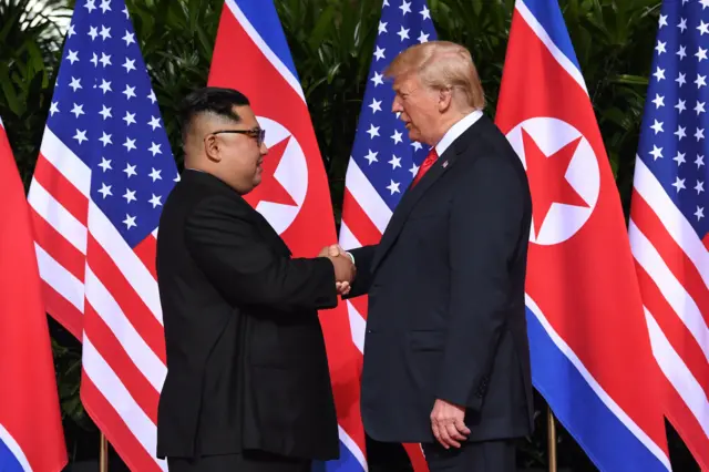 North Korea"s leader Kim Jong Un (L) shakes hands with US President Donald Trump (R) at the start of their historic US-North Korea summit