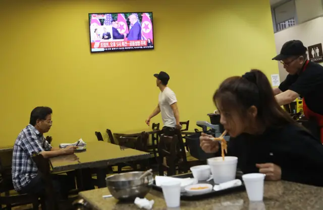 Koreatown residents watch the talks over at a noodle restaurant