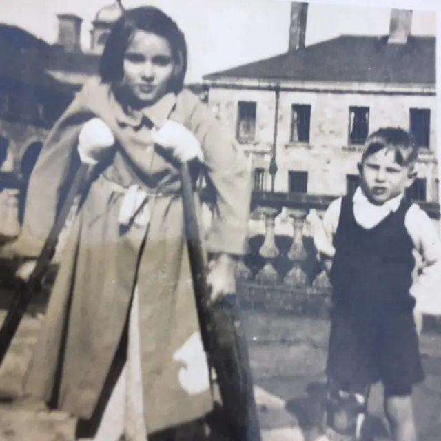 A black and white image of Valerie as a young girl on crutches. There is also a young boy in the right hand side of the picture