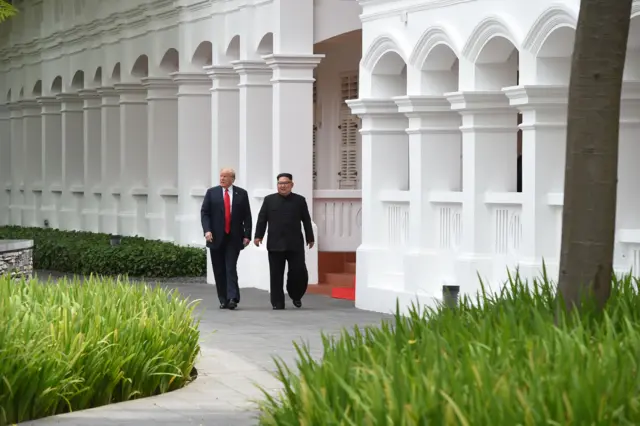 North Korea"s leader Kim Jong Un (R) walks with US President Donald Trump (L) during a break in talks at their historic US-North Korea summit,