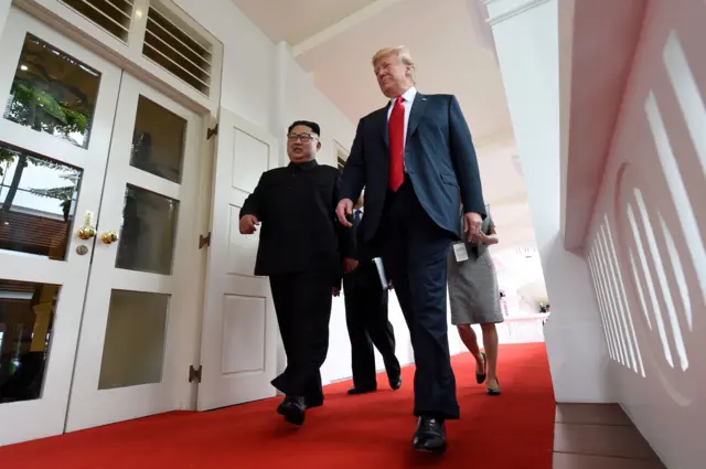 North Koreas leader Kim Jong Un (L) walks with US President Donald Trump (R) at the start of their historic US-North Korea summit,