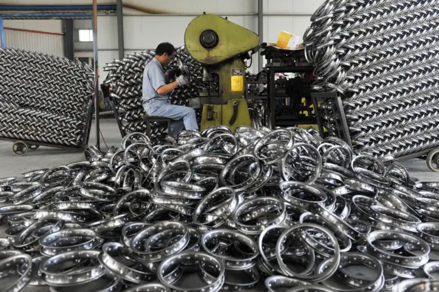 A worker welds wheel hubs for prams at a factory in Hangzhou in China"s eastern Zhejiang province