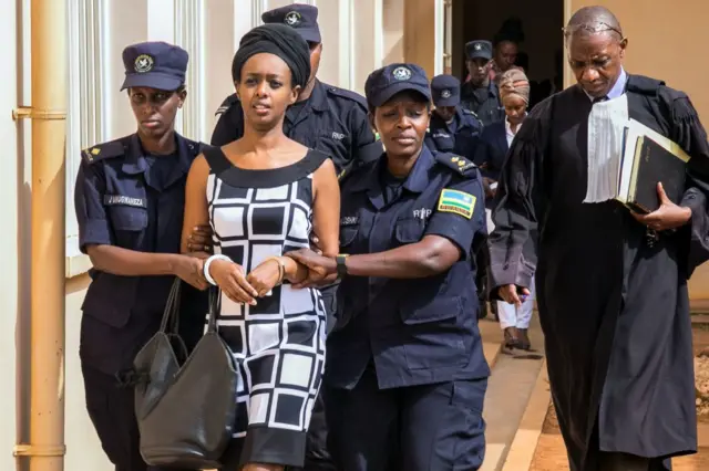 Diane Rwigara (C), a prominent critic of Rwanda's President Paul Kagame, is escorted by Police officers to the court room at the Nyarugenge intermediate court in Kigali on October 9, 2017