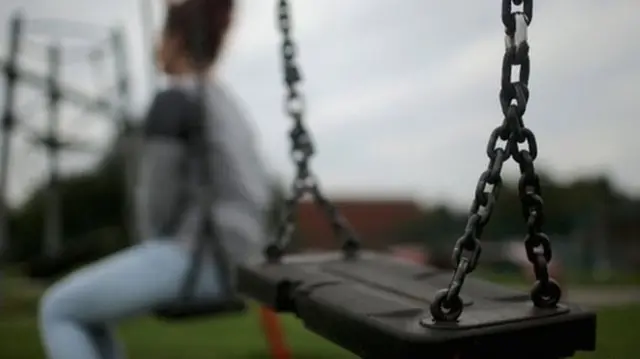 Girl out of focus sat on a swing