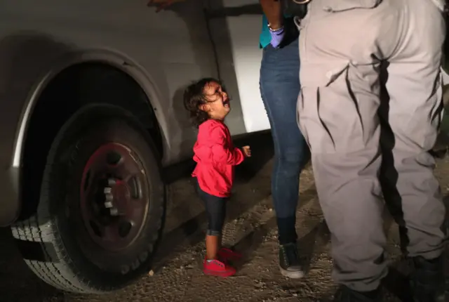 A two-year-old Honduran asylum seeker cries as her mother is searched and detained near the U.S.-Mexico border