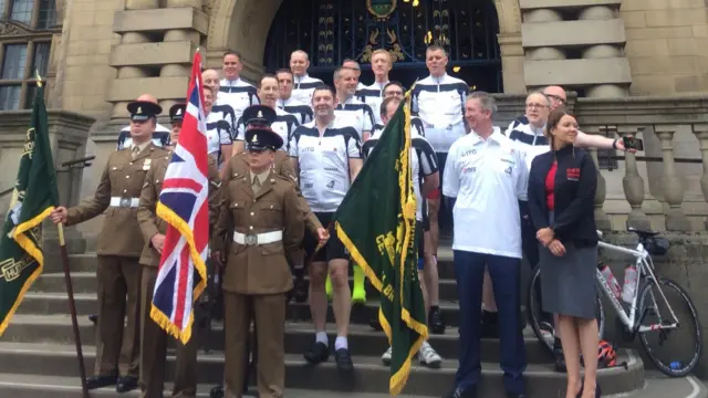 Riders stand outside the town hall with their bikes