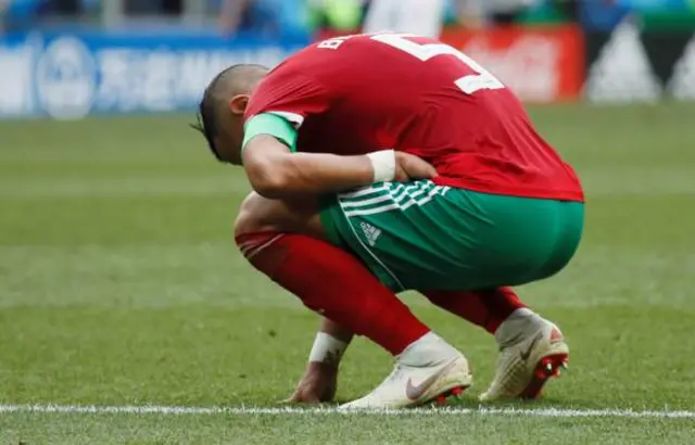 A Moroccan footballer crouches on the ground after losing the match