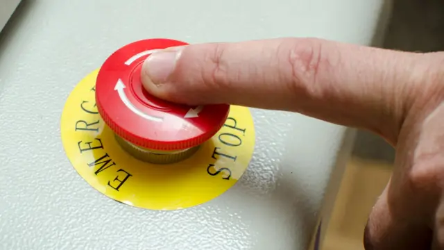 A finger on an emergency stop button