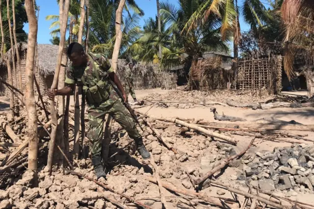 Mozambican Army soldiers bring down a structure torched by attackers to be rebuilt as shelter for people fleeing the recent attacks, in Naunde, northern Mozambique, on June 13, 2018