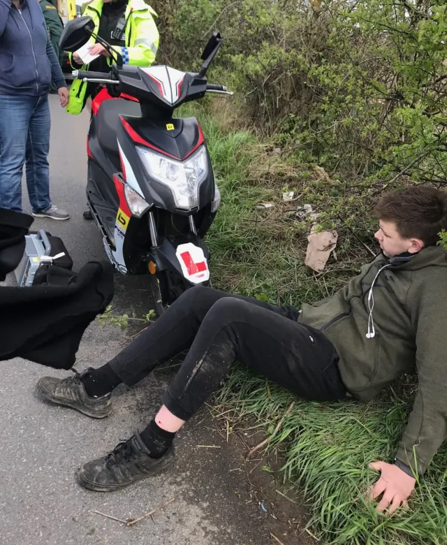 Boy on the floor next to moped