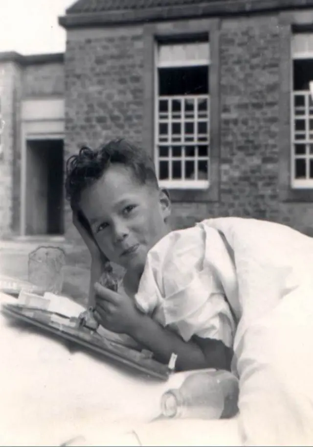 Bill Ross as a child lying on a hospital bed outside