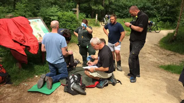 Paramedics and rescue team tend to a fallen mountain bike rider on the floor.