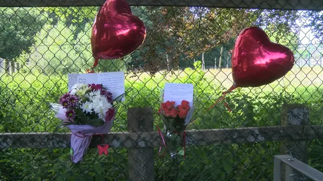 Heart balloons and flowers tied to a fence