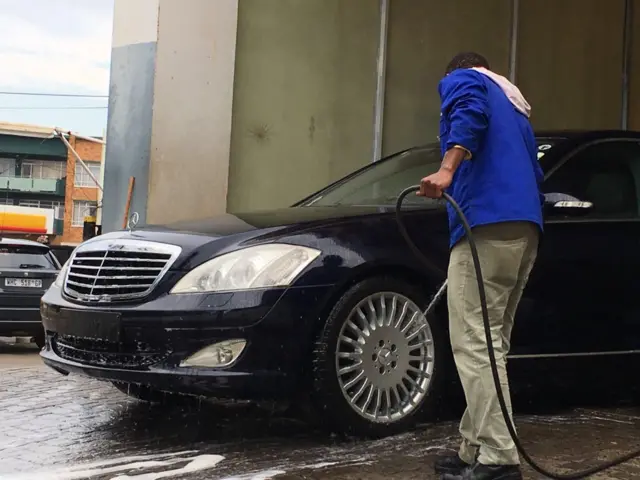 A man washes a Mercedes Benz car