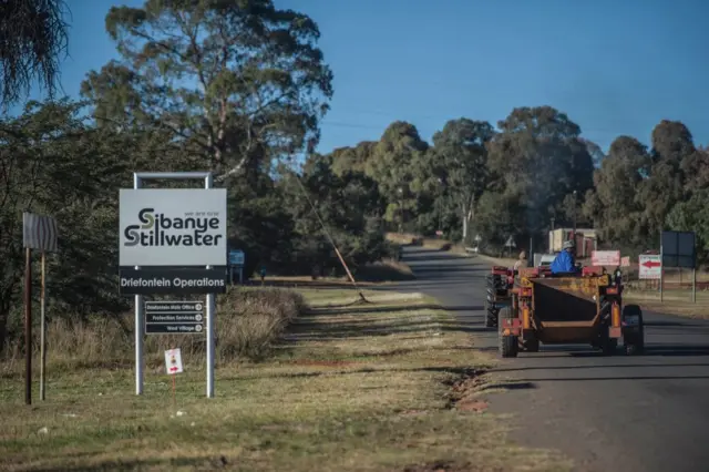 Workers drive past a sign of the Sibanye-Stillwater Driefontein gold mine near Carletonville, near Johannesburg, on May 5, 2018.