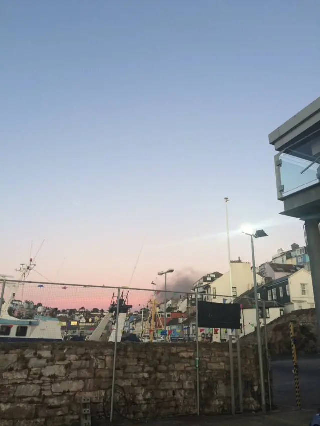 view from harbour with smoke billowing into the skyline