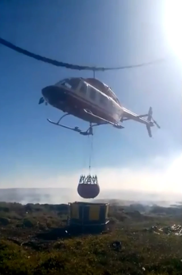 A helicopter delivers water on Saddleworth Moor