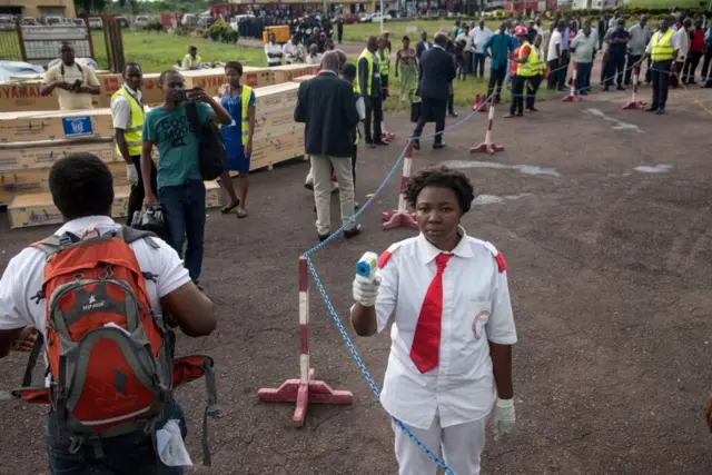 A health official uses a thermometer to measure the temperature of disembarking passengers at the airport at Mbandaka in DRCongo on May 19, 2018