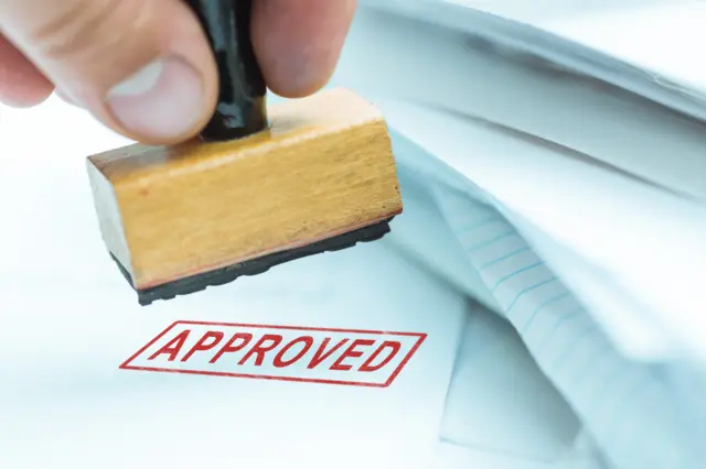 A document being stamped as 'approved'