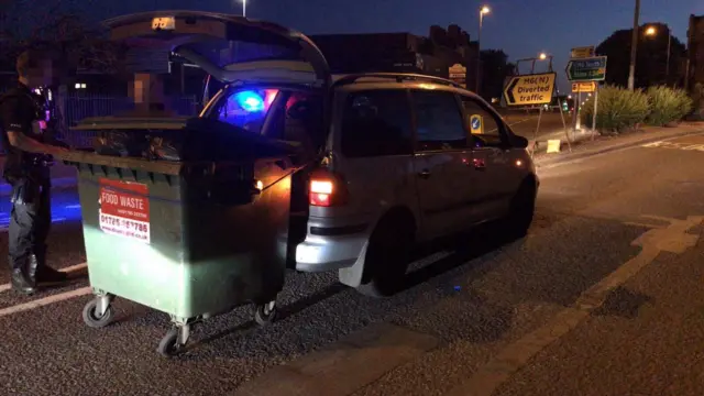 Car pulling a bin